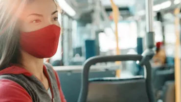 Woman wearing a red mask on a bus.