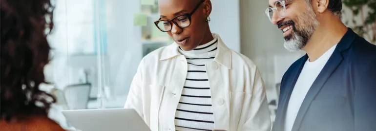 Trois collègues discutent d'un projet en regardant une tablette.